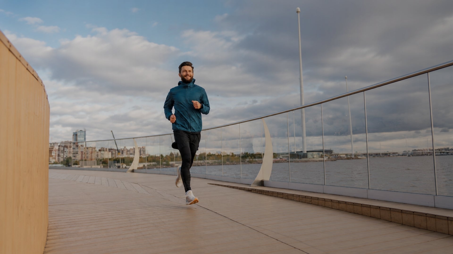 fit man jogging on scenic waterfront path during cloudy day