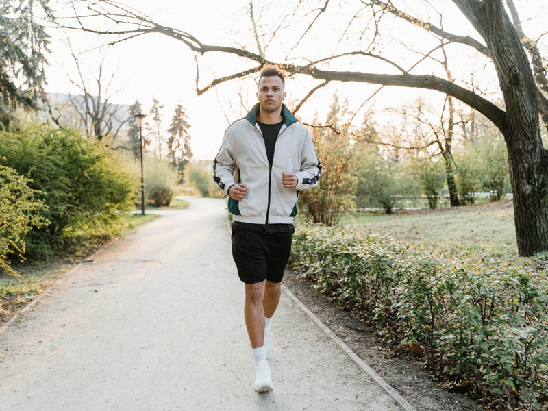 fit man jogging along scenic park pathway during sunny afternoon