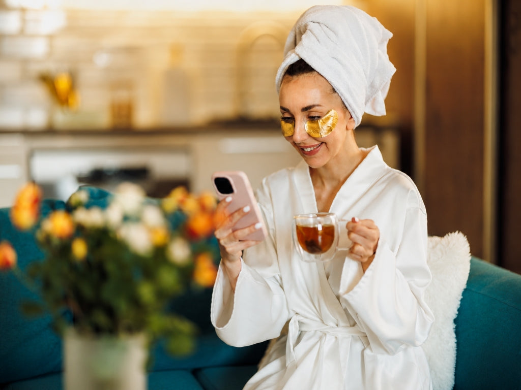 smiling woman applying skincare product to her glowing healthy face