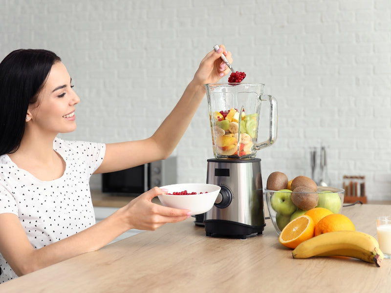 woman making healthy smoothie
smiling woman adding fresh berries into blender for healthy smoothie